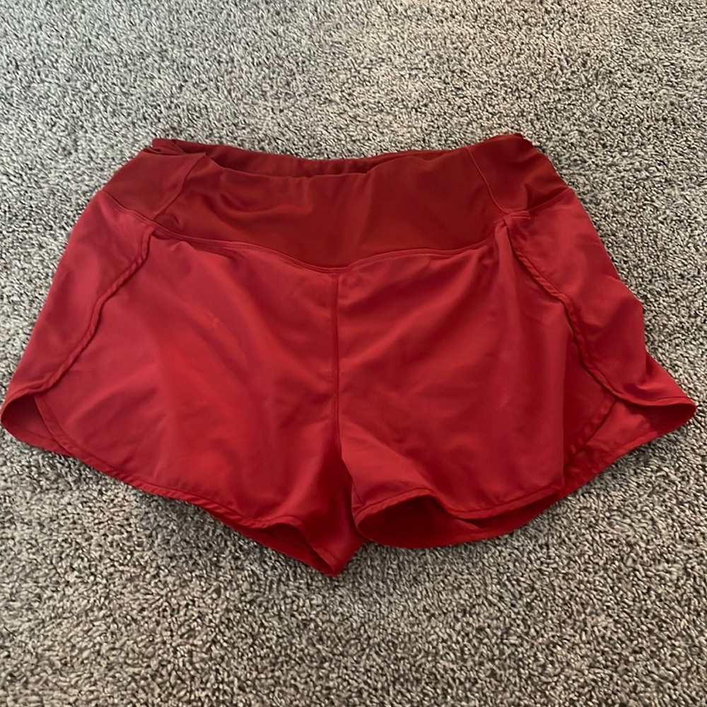 Red athletic shorts with built in pockets and zippered pocket. Size L